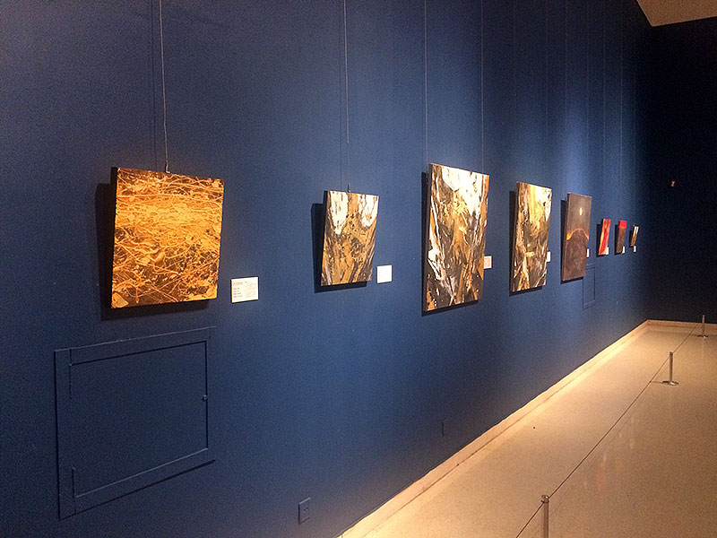 Installation view showing a series of medium-scale abstract Nihonga paintings arranged in a row on a blue wall